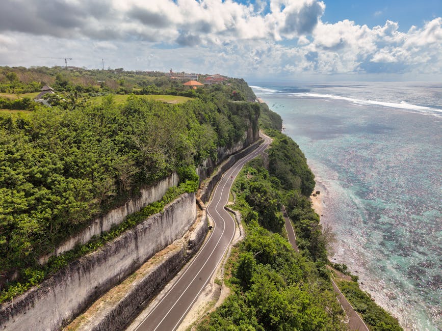 A picturesque aerial view of a winding coastal road alongside cliffs and ocean in Bali, Indonesia.
