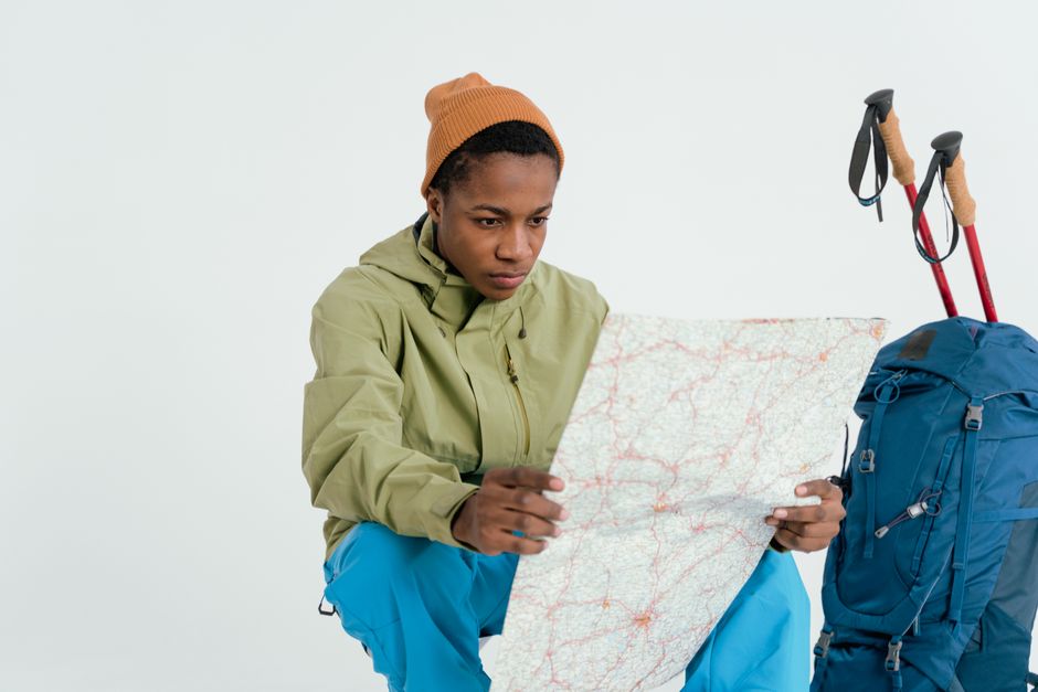 A young man with a backpack examines a map, preparing for an adventure.