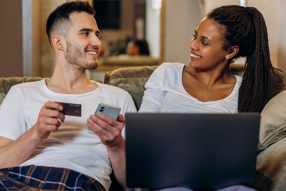 Interracial couple enjoying online shopping together with a laptop and credit card.