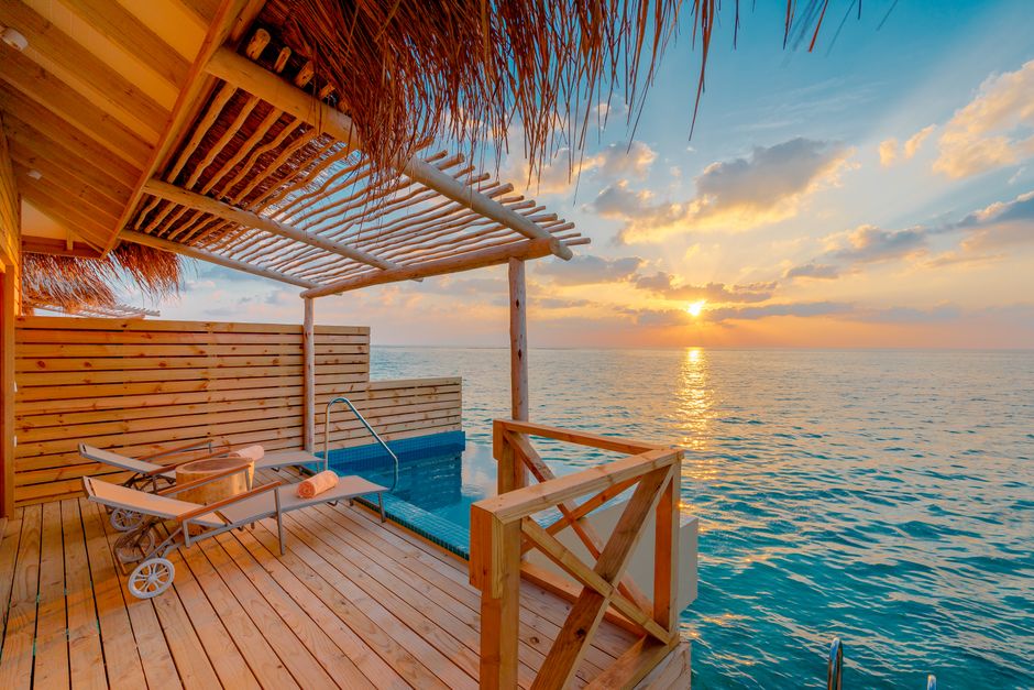Experience ultimate relaxation in a sunset view overwater bungalow in the Maldives.
