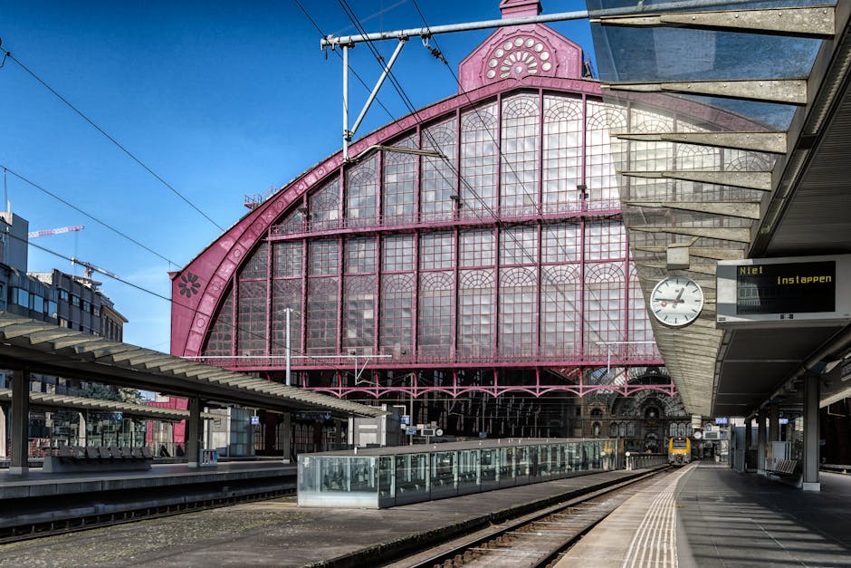 Empty railway platform with historic architecture under blue sky.