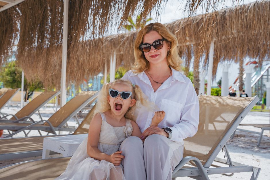 A joyful moment of a mother and daughter on sunbeds at a sunny beach in Kemer, Antalya.