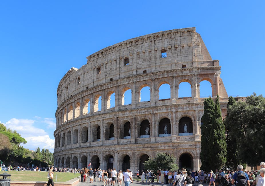 Iconic Colosseum in Rome, Italy, bustling with tourists on a sunny day.