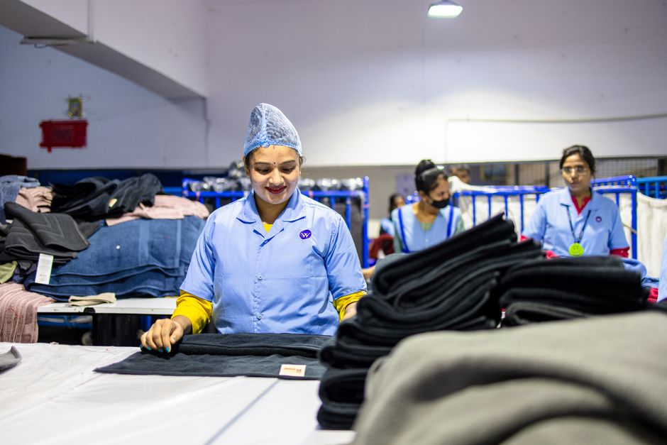 Female workers in blue uniforms sorting textiles in a factory setting.