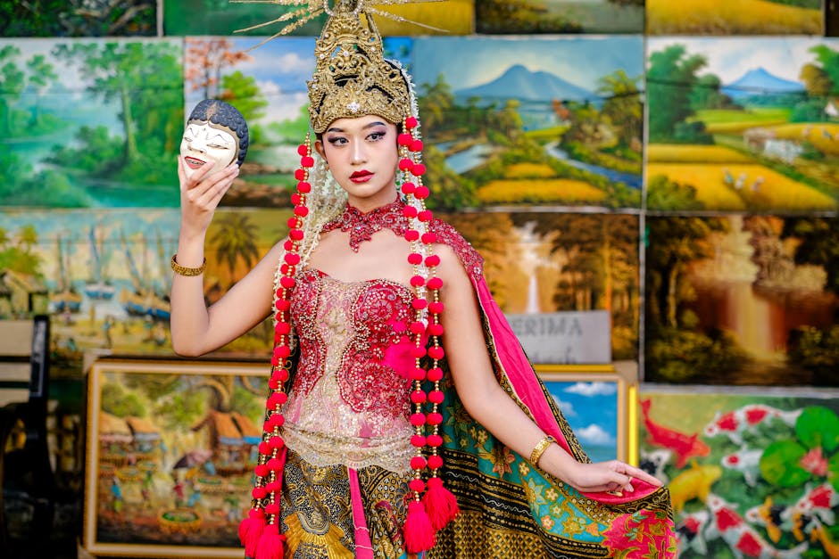 Portrait of a woman in traditional Indonesian attire holding a mask, showcasing cultural heritage.