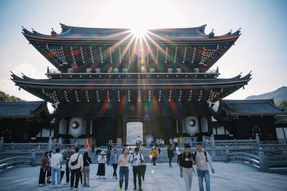 Visitors enjoying a sunny day at a traditional Japanese temple, showcasing stunning architecture.