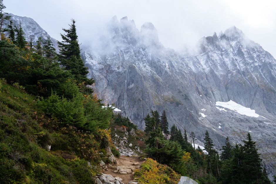 Explore the misty autumn trails in North Cascades, Washington, featuring dramatic mountain views.