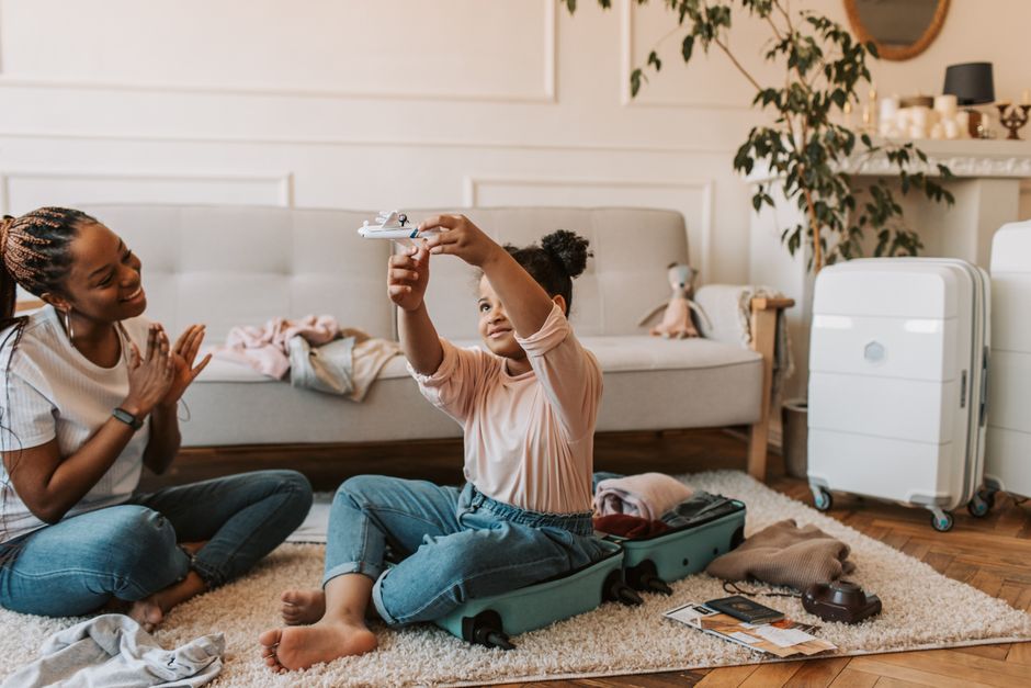 A joyful mother and daughter interacting at home while preparing luggage, filled with warmth and happiness.