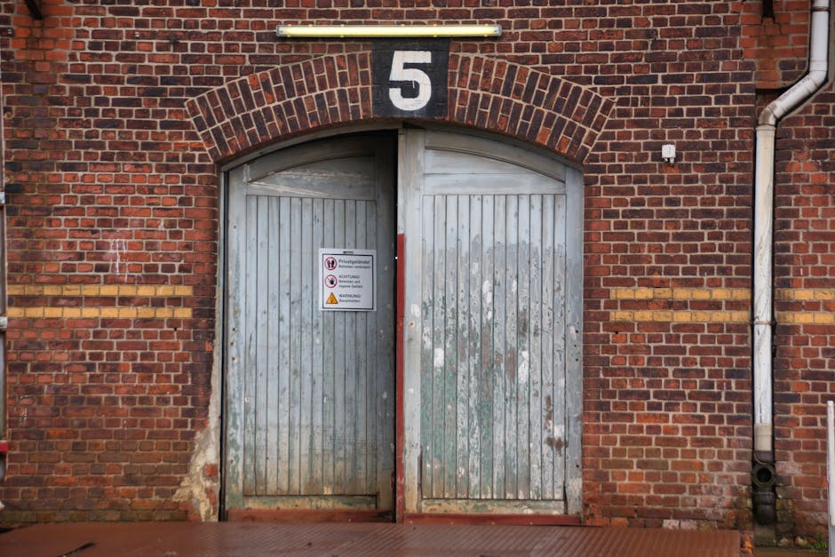 Historic brick facade in Hamburg featuring weathered wooden doors and numbered sign.