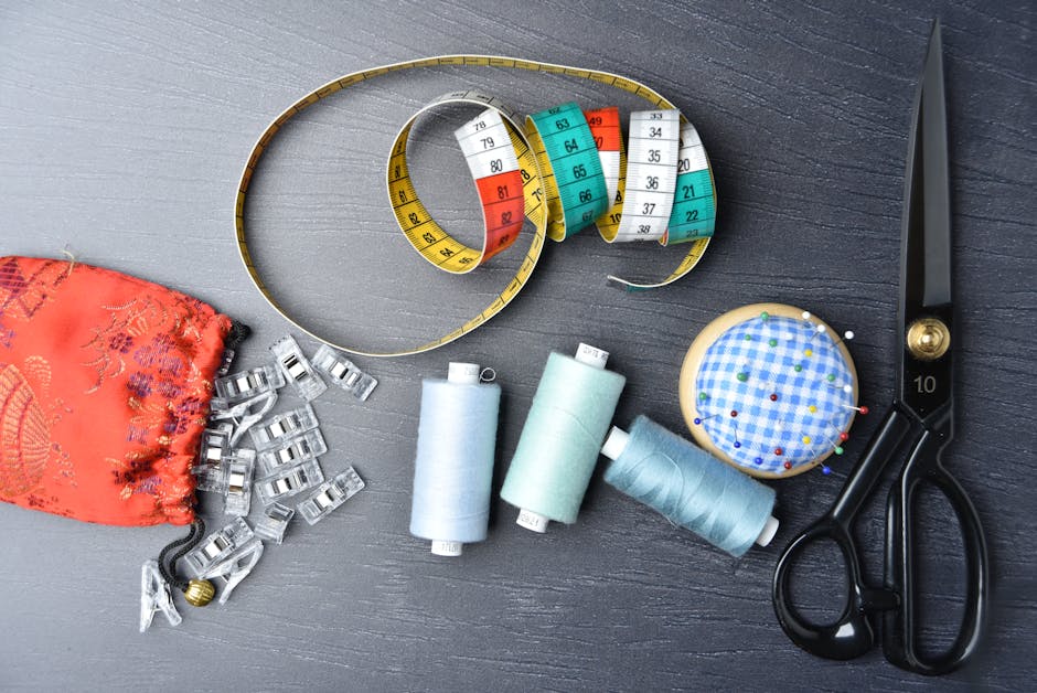 A vibrant arrangement of sewing tools including thread, tape measure, and scissors on a dark background.