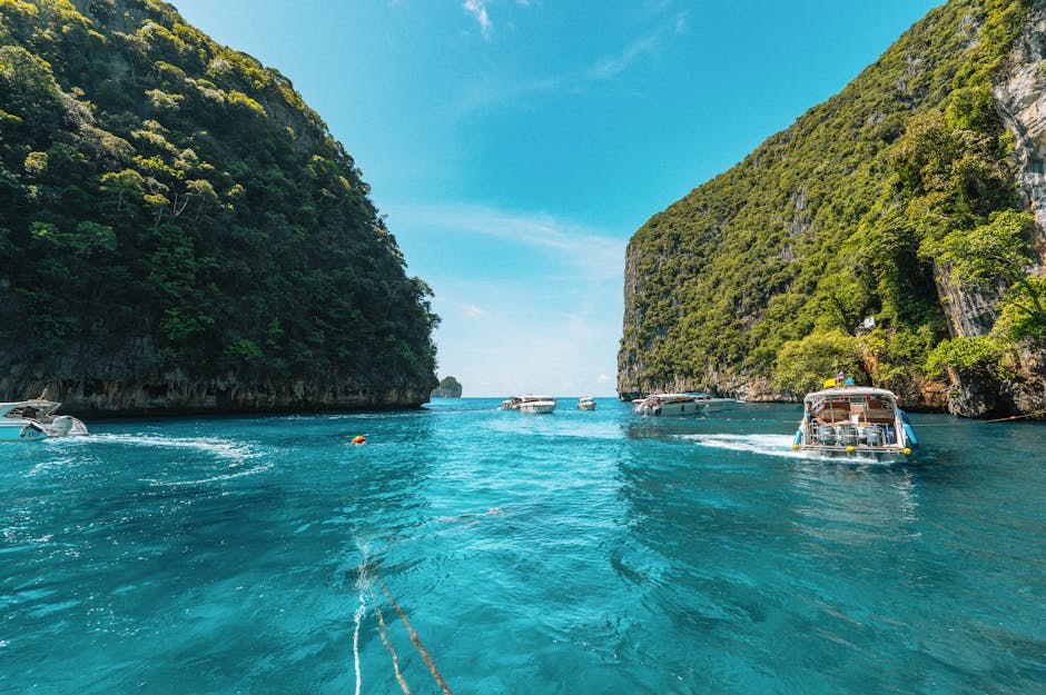 Explore the clear waters and lush cliffs of Krabi, Thailand, with boats navigating between stunning formations.